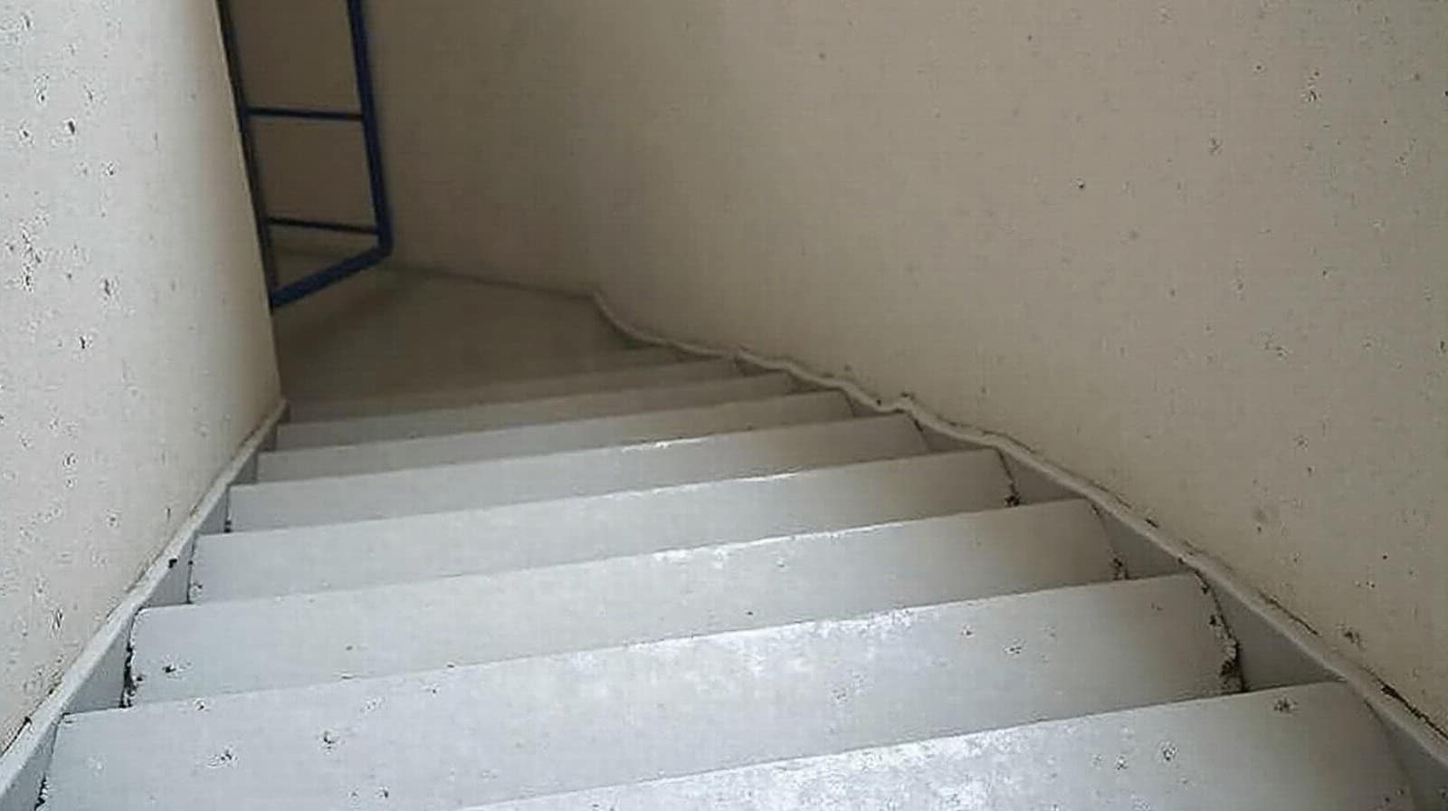 Vue rapprochée d'un sol en béton ciré fini dans une cage d'escalier d'immeuble collectif, aucune personne visible
