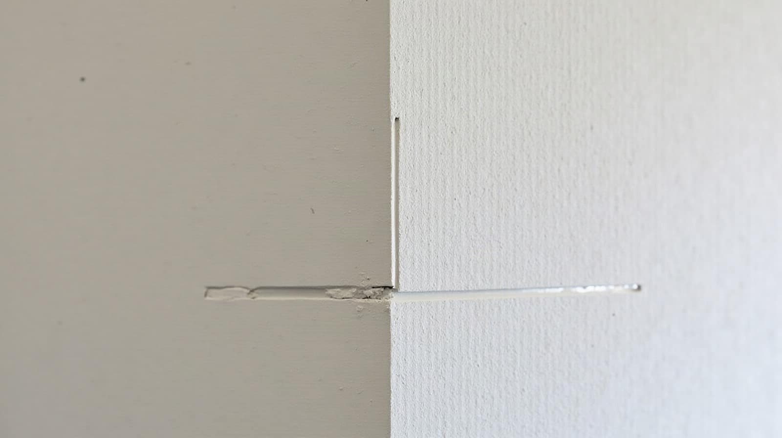 Détail d'un angle de mur et d'un joint de sol examinés au niveau avant travaux, sans personne visible